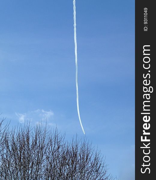 A hard to see airplane and its chemtrail high in the blue sky. A hard to see airplane and its chemtrail high in the blue sky.