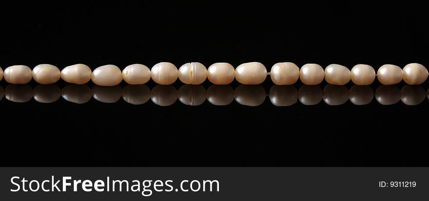 A pearl necklace on black background. A pearl necklace on black background.