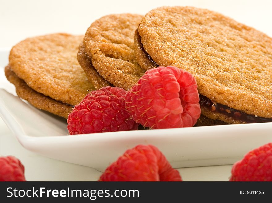 Raspberry ginger snaps on square white plate with raspberries