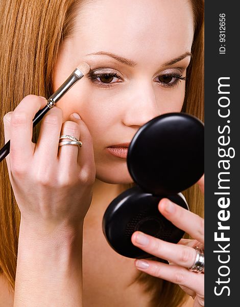 Nice caucasian model applying makeup with brush. Nice caucasian model applying makeup with brush