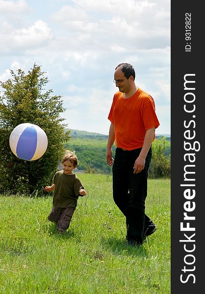 Father and son playing football on nature