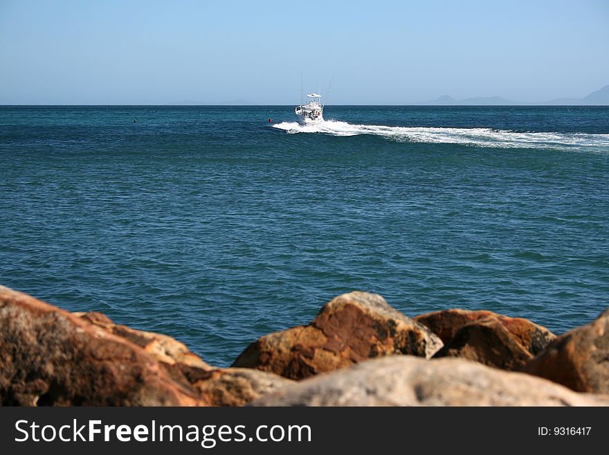 Boat in the far away distance with rocks in the foreground. Boat in the far away distance with rocks in the foreground