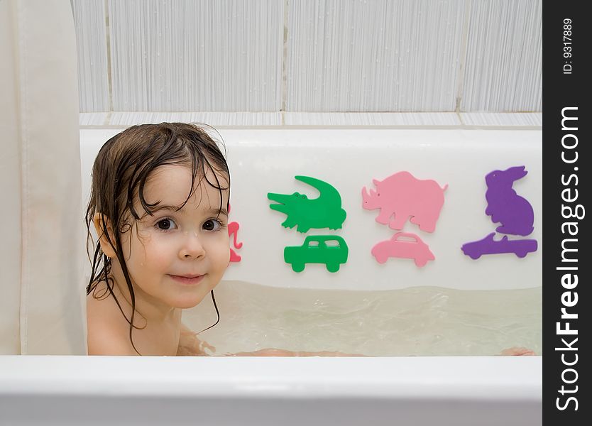 Little girl take a bath with toys