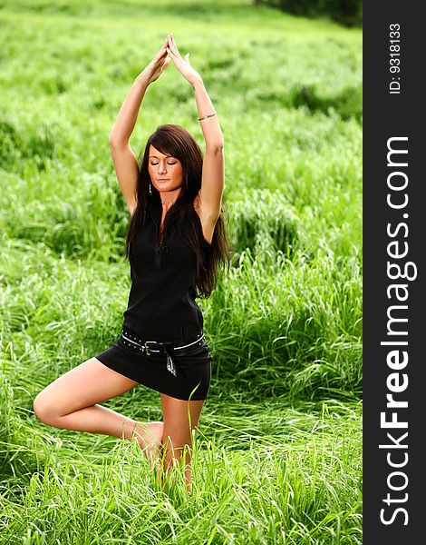 An attractive woman is doing mediation on a big green meadow field to find the peace of mind. An attractive woman is doing mediation on a big green meadow field to find the peace of mind