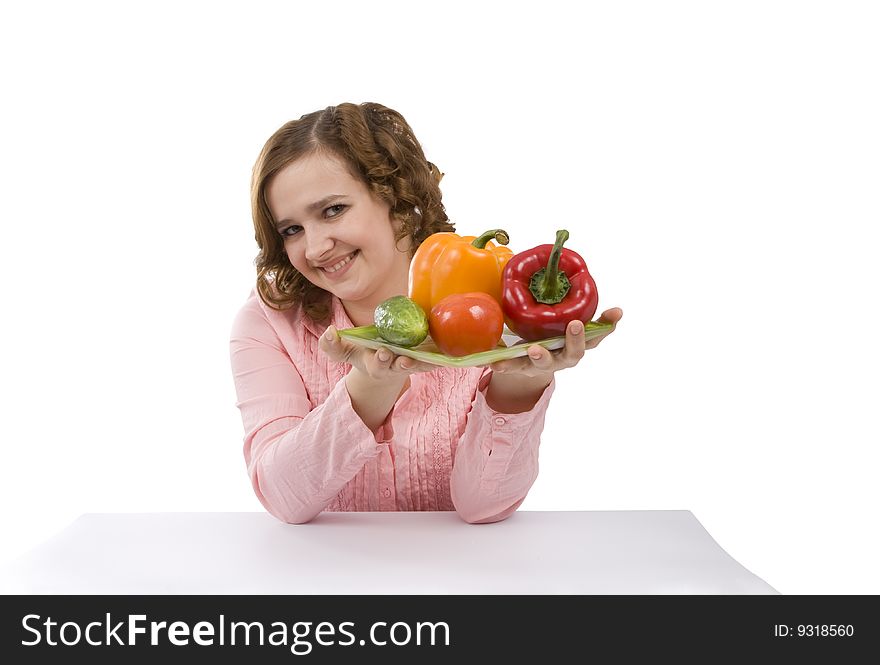 Pretty girl with fresh vegetables.  Housewife is holding the plate with pepper, tomato, cucumber.  Isolated over white background. Pretty girl with fresh vegetables.  Housewife is holding the plate with pepper, tomato, cucumber.  Isolated over white background.