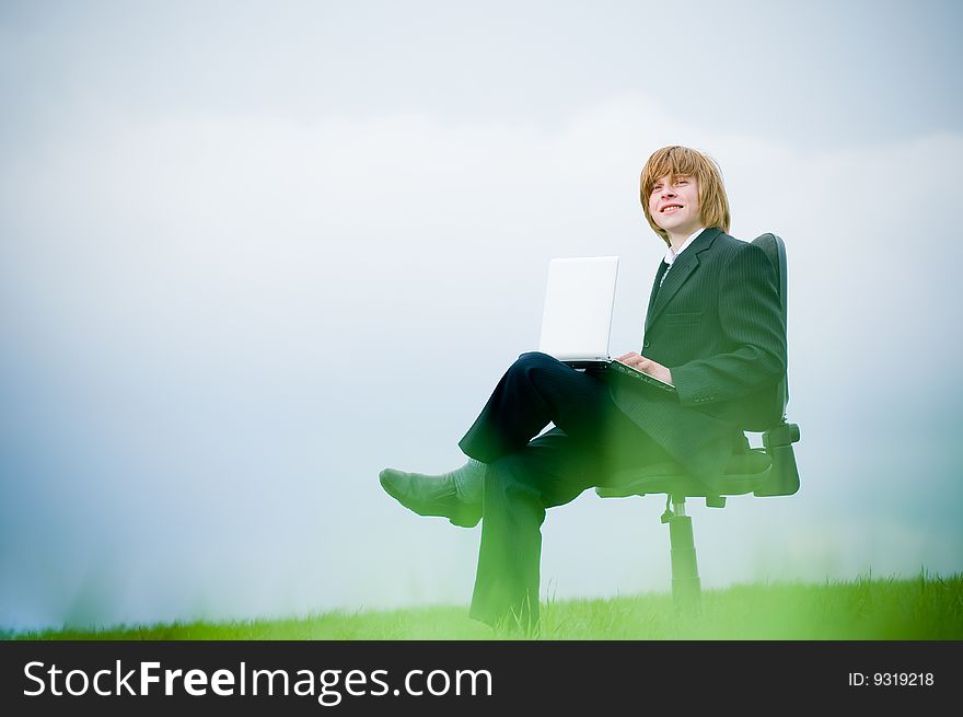 Smiling young businessman with laptop outdoors