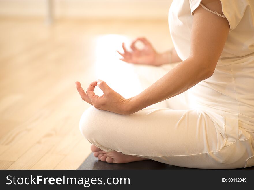 Beautiful woman sitting in lotos pose and practicing meditation in yoga hall