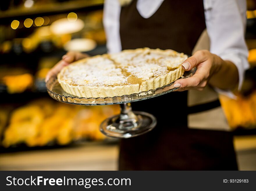 Closeup of bakery female worker posing with apple tart in bakery