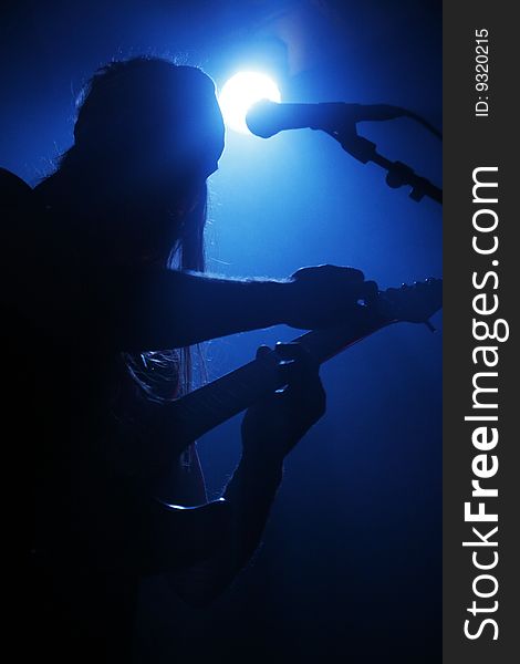 A silhouette of a guitar player in blue lighting. A silhouette of a guitar player in blue lighting