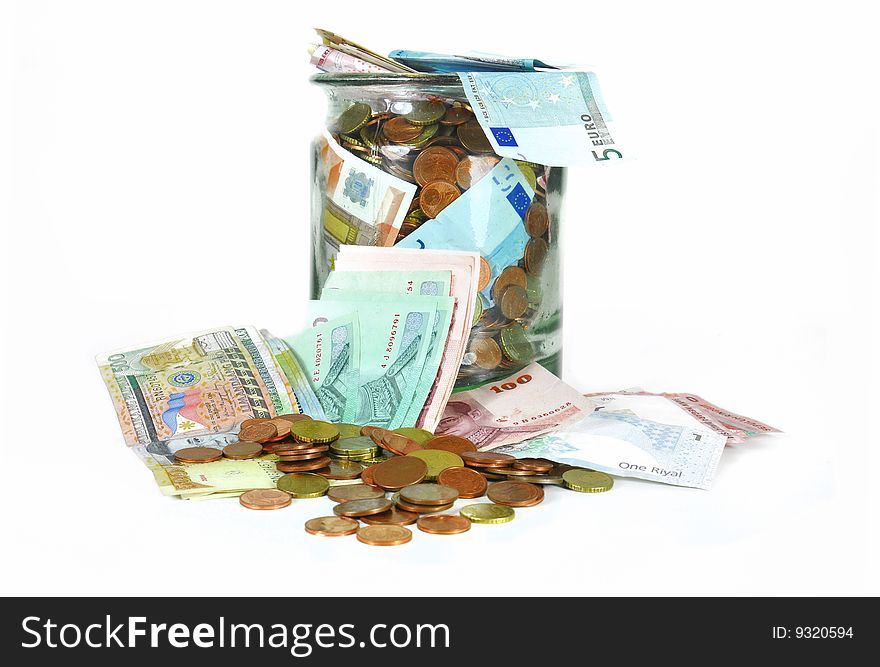 Glass money jar full of different currencies isolated on white. Glass money jar full of different currencies isolated on white