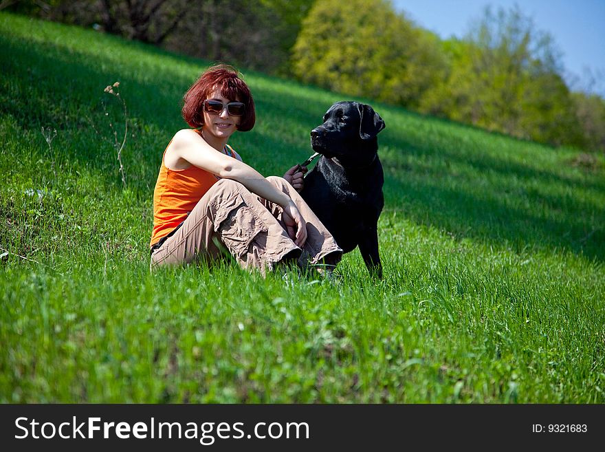 The young woman with black labrador on a green grass. The young woman with black labrador on a green grass