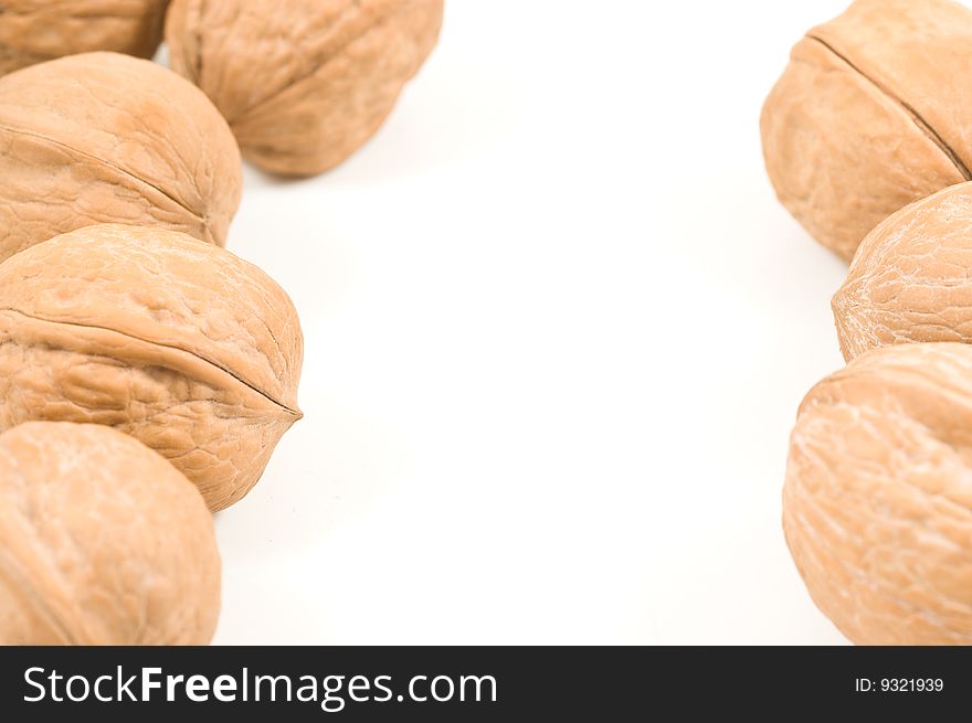 Walnuts on white background, forming a frame.