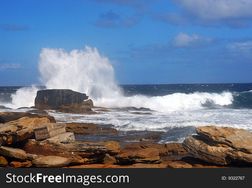 Sea waves hitting on yellow rocks with high flashes
