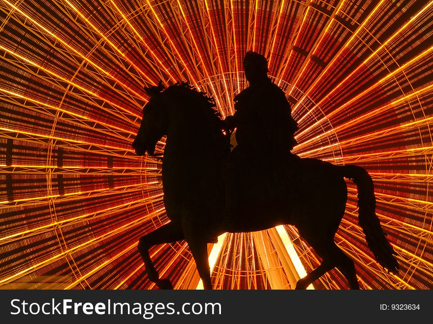 The equestrian statue of King Louis XIV is silhouetted against a giant ferris wheel at the Place Bellecour in Lyon France. The equestrian statue of King Louis XIV is silhouetted against a giant ferris wheel at the Place Bellecour in Lyon France.