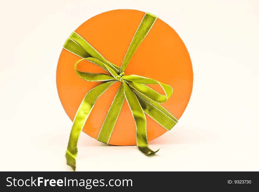 A present in an orange box tied with a green ribon with silver trim. A present in an orange box tied with a green ribon with silver trim.