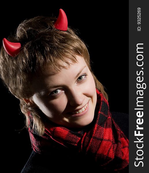 A young smiling sexual girl in an image of a devil in red and black with horns on her head posing on a dark background. A young smiling sexual girl in an image of a devil in red and black with horns on her head posing on a dark background