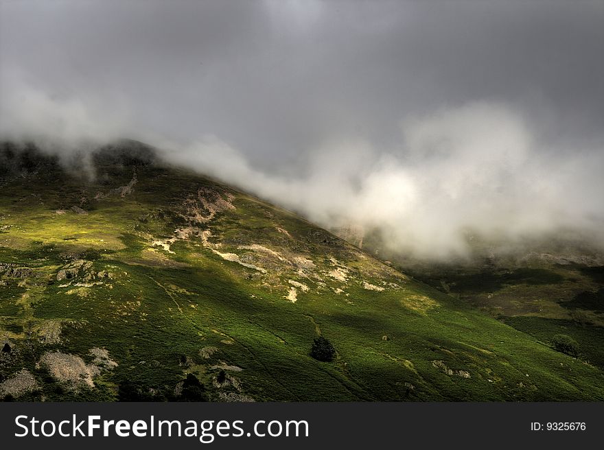 Hill at the Lake District UK with heavy clouds hanging over it, view from Hardknott pass