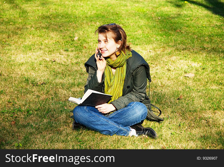 A young girl on a lawn talking by cellular phone. A young girl on a lawn talking by cellular phone