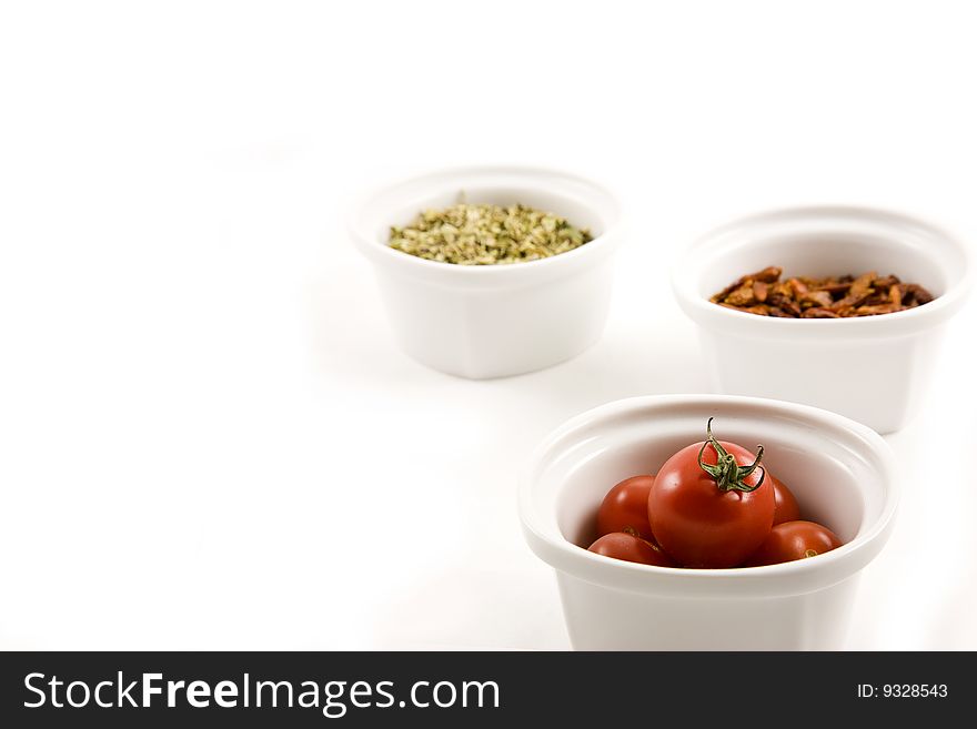 A set of modern minimalist white bowls with Mediterranean ingredients. Oregano, chillies, tomatoes