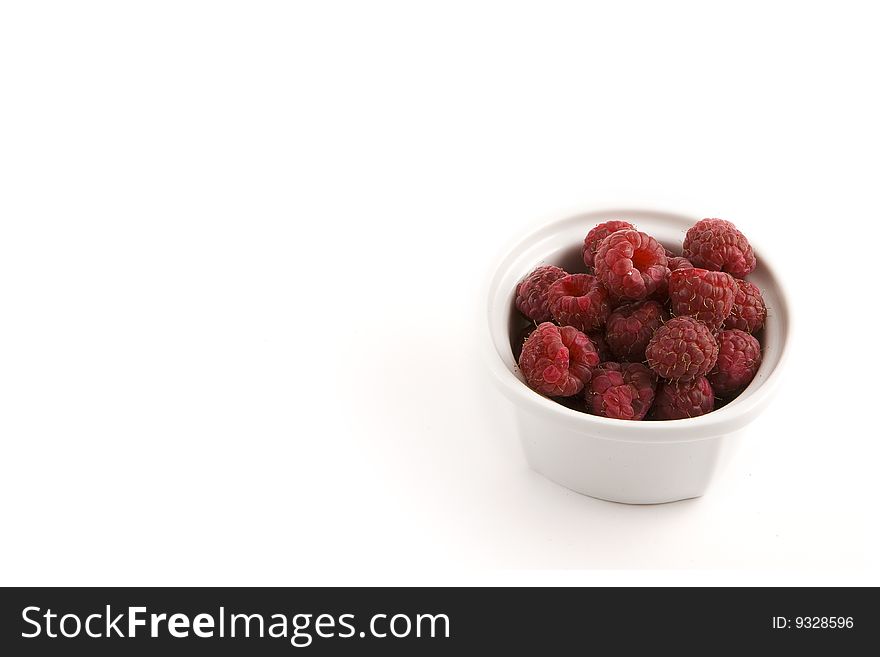 A modern minimalist white bow full of raspberries, ready to be served. A modern minimalist white bow full of raspberries, ready to be served