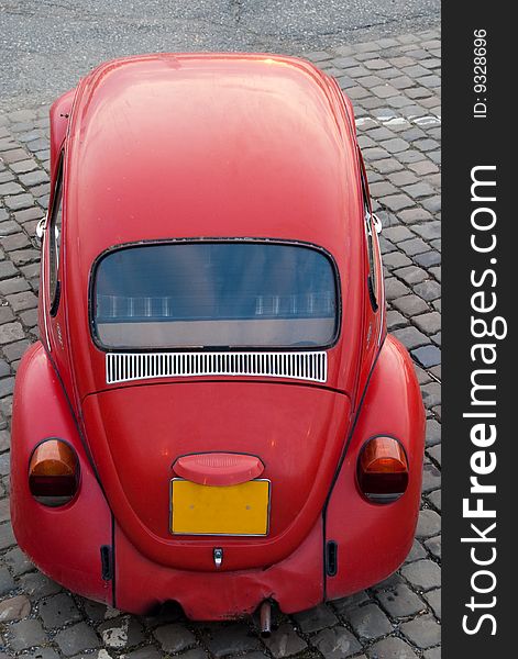 A front view of an old red volkswagen beetle, parked on an old brick surface. A front view of an old red volkswagen beetle, parked on an old brick surface