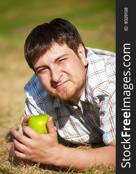 The man with an green apple on the sunlight