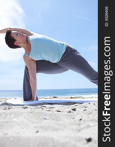 An attractive woman practicing yoga at the beach. An attractive woman practicing yoga at the beach