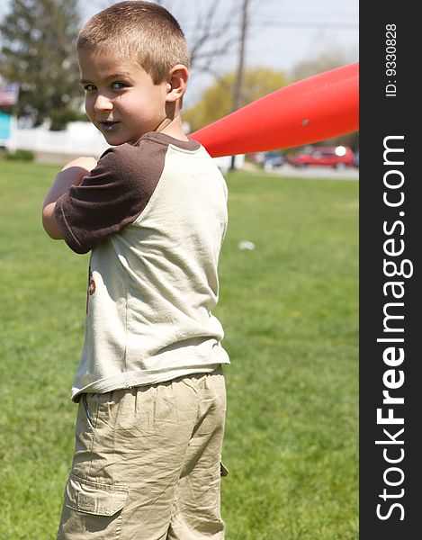 Cute boy holding his plastic red baseball bat. Cute boy holding his plastic red baseball bat
