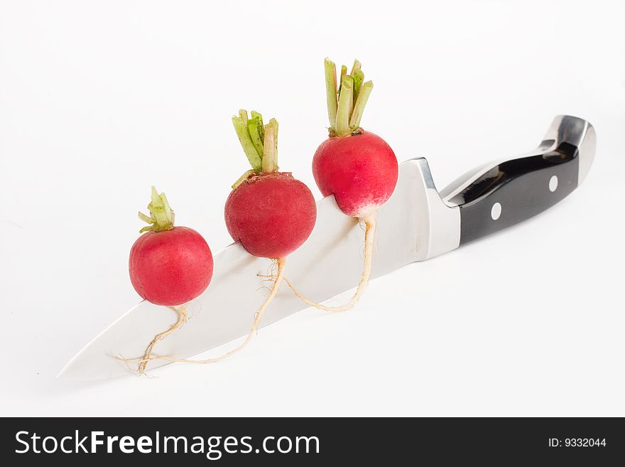 Three red radishes fixed on a knife  blade. Three red radishes fixed on a knife  blade