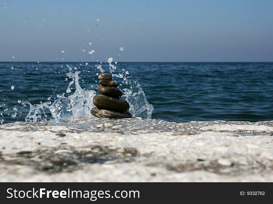 Splashing water and pile of stones on the beach. Splashing water and pile of stones on the beach