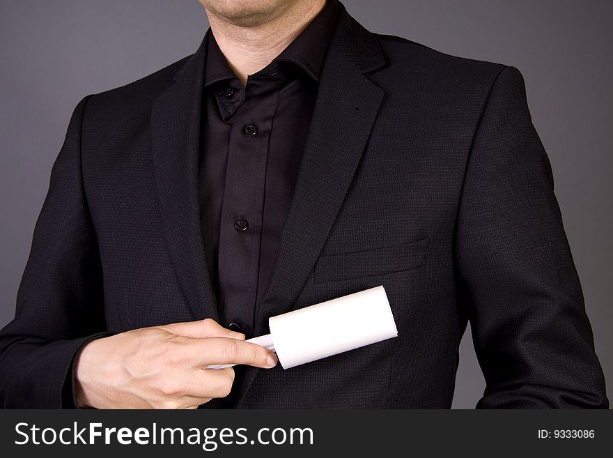 An adult male is cleaning his business suit with a fuzz roller. An adult male is cleaning his business suit with a fuzz roller