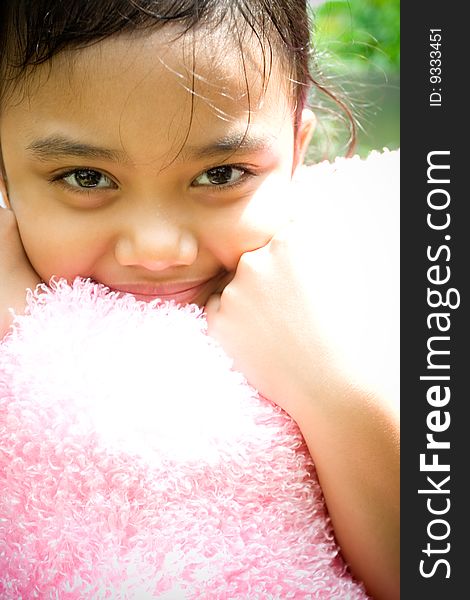 Portrait of sweet asian little girl hugging a pink pillow and smiling at camera. Portrait of sweet asian little girl hugging a pink pillow and smiling at camera