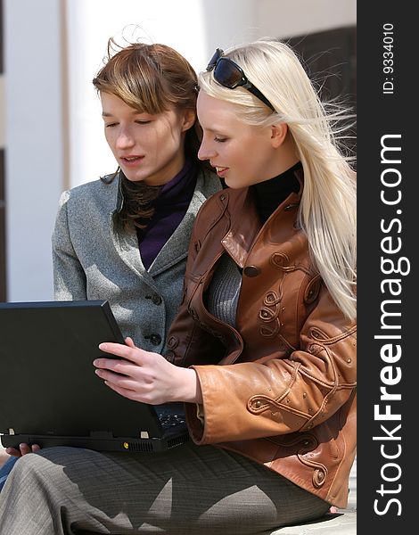 Two women working on laptop outdoor. Two women working on laptop outdoor