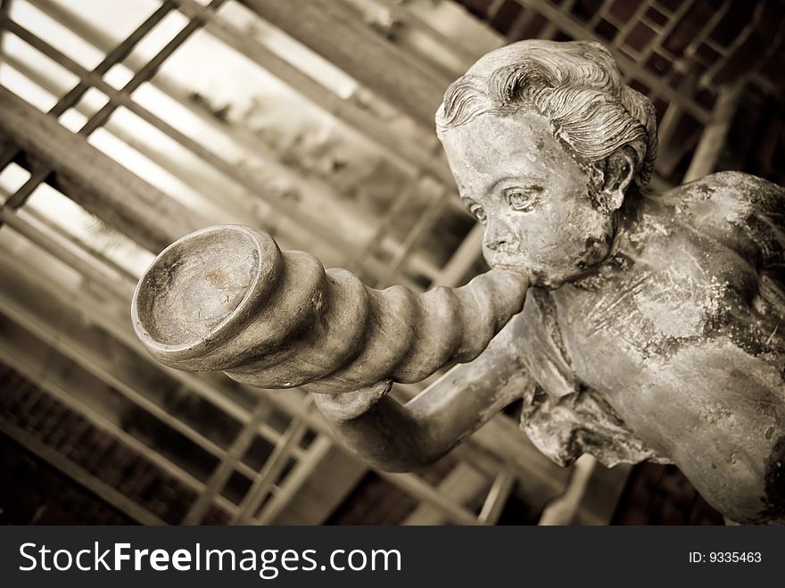 Cupid blowing horn.Aged photo style.Shallow depth of field with focus on the closest part of the horn.