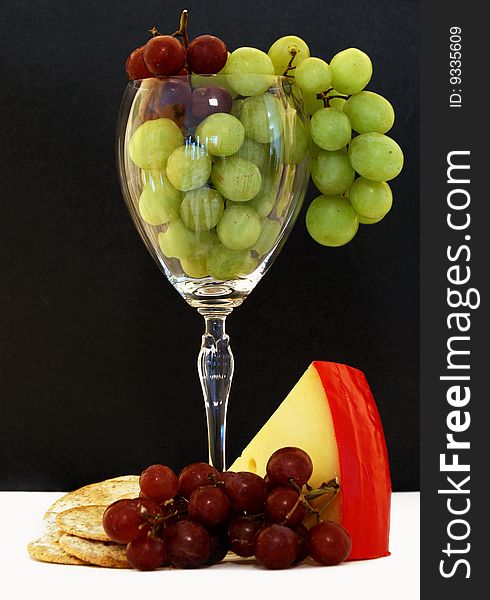 Grapes, crackers, and cheese in and around a wine glass. Grapes, crackers, and cheese in and around a wine glass