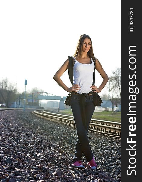 Brunette model standing on railroad in her jeans and pink gymshoes. Brunette model standing on railroad in her jeans and pink gymshoes