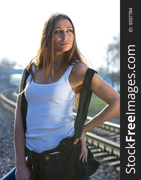 Brunette model standing on railroad in her jeans and pink gymshoes. Brunette model standing on railroad in her jeans and pink gymshoes