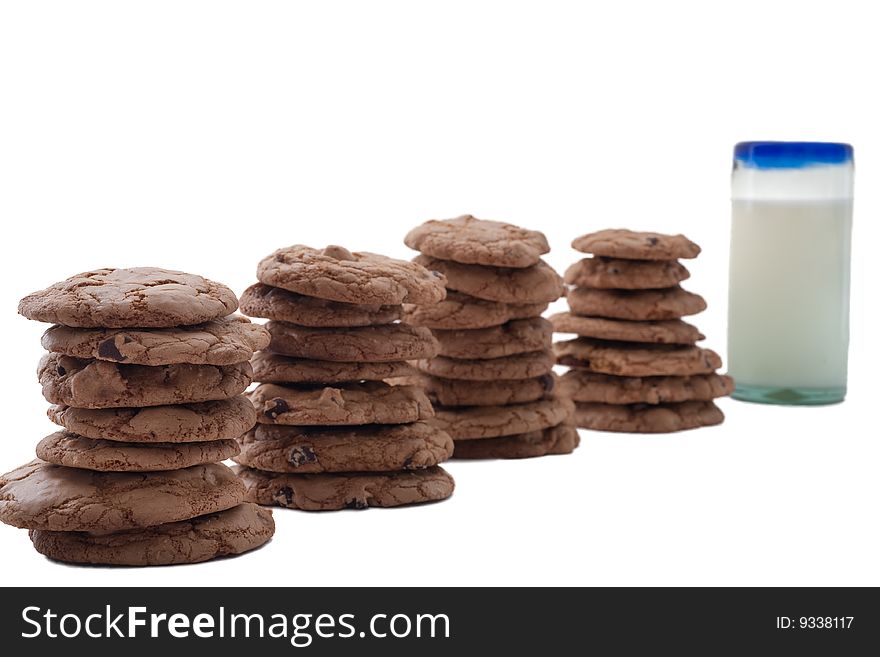 Stacks of chocolate chip cookies arranged in a row, ending in glass of milk. Stacks of chocolate chip cookies arranged in a row, ending in glass of milk.