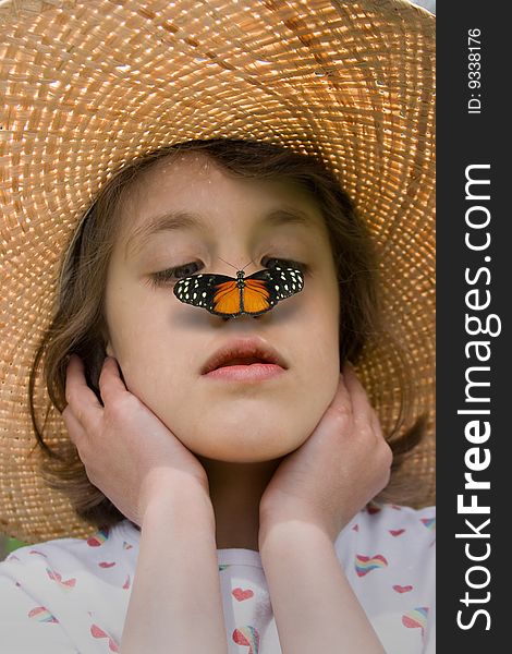 A child in a straw hat with a butterfly on her nose. A child in a straw hat with a butterfly on her nose