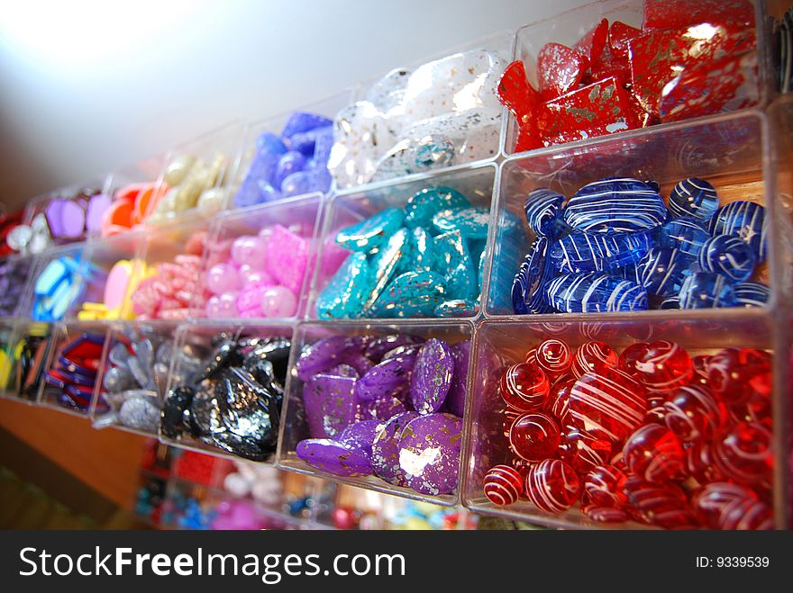 Multicoloured beads sorted in boxes for sale in bijouterie shop