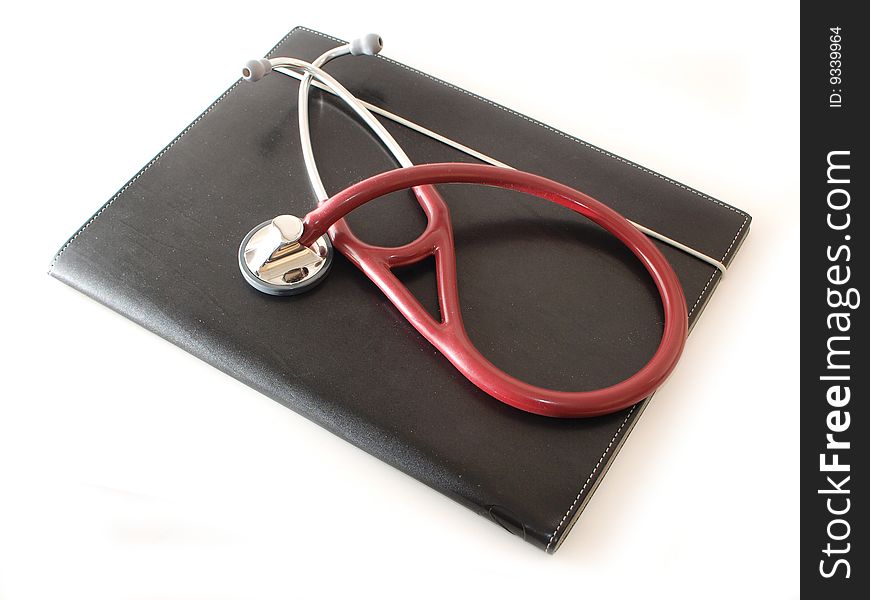 A maroon stethoscope on a black compendium isolated on white. A maroon stethoscope on a black compendium isolated on white