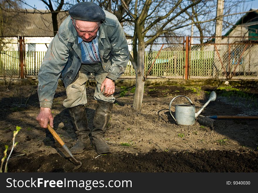 An  old peasant cultivating the soil in his kitchen garden in the countruside. An  old peasant cultivating the soil in his kitchen garden in the countruside