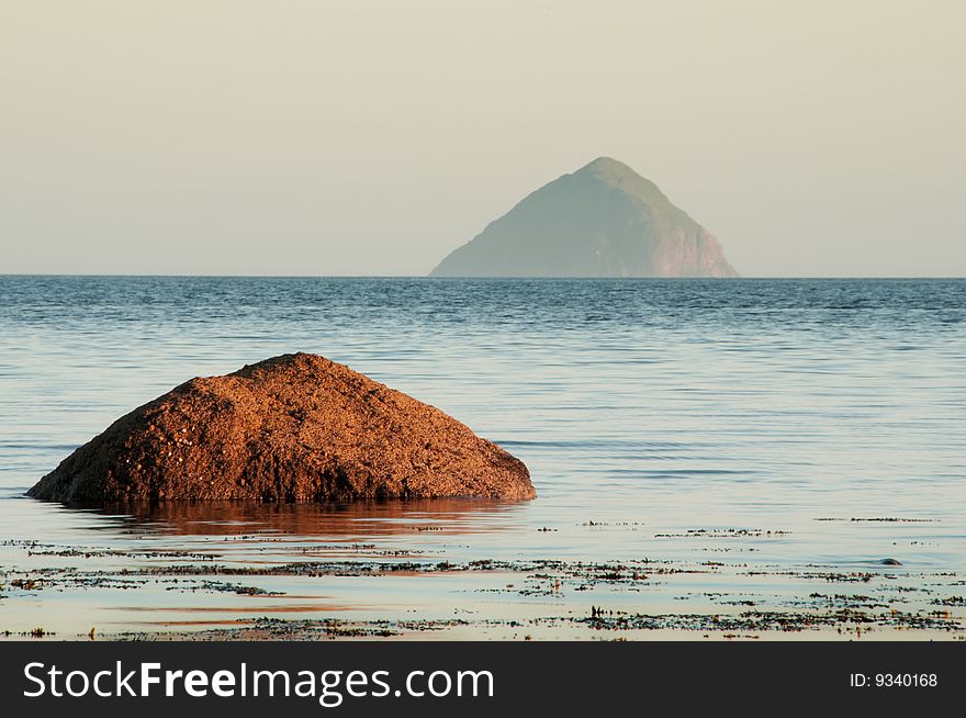 Ailsa Craig Island with rock in the sea in fore ground