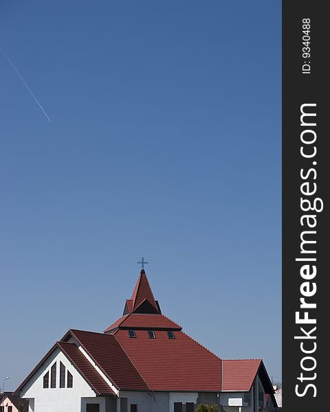 The red roof of a modern church against blue sky. The red roof of a modern church against blue sky.