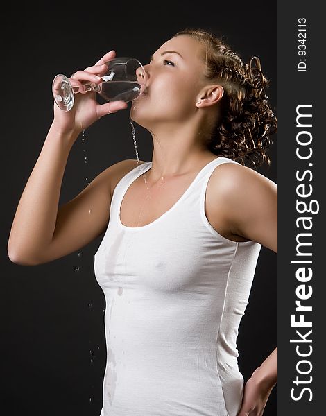 Beautiful girl in a white vest drinks water from a glass. Beautiful girl in a white vest drinks water from a glass