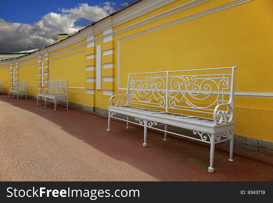 Town of Pushkin, Russia. White metal benches in a court yard of the Tsarskoselsky palace in St.-Petersburg. Town of Pushkin, Russia. White metal benches in a court yard of the Tsarskoselsky palace in St.-Petersburg