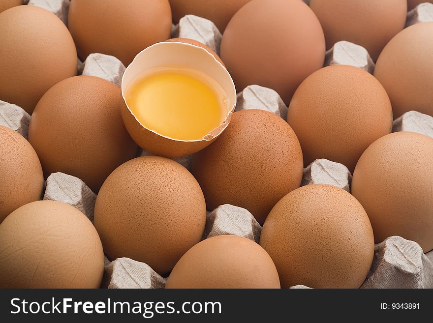 Close up on raw brown eggs in an egg carton, at an angle of 45 degrees, one broken