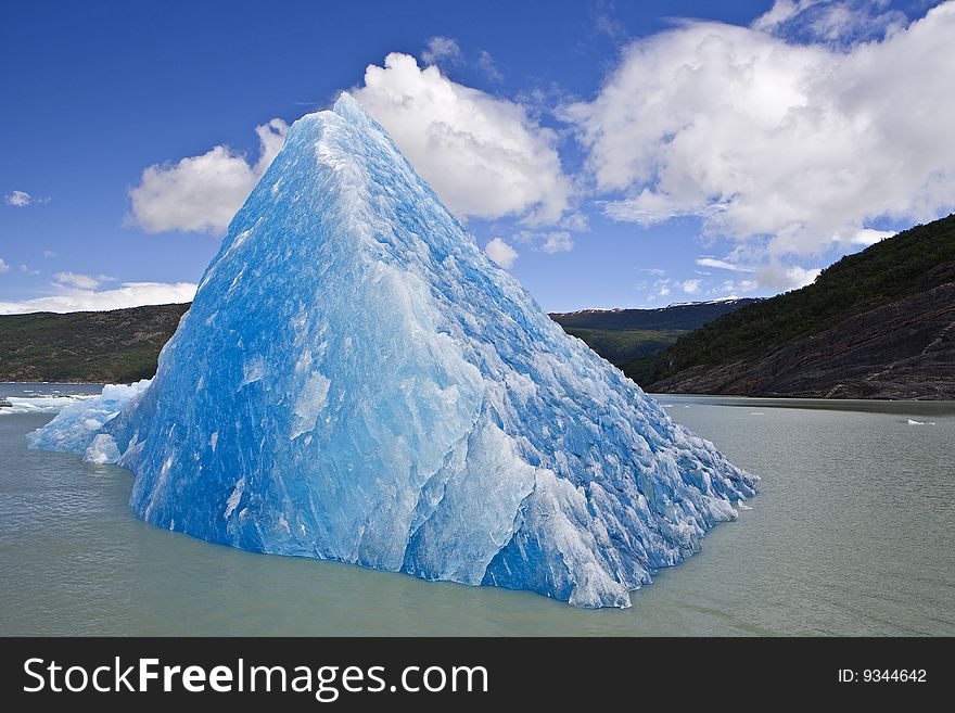 Blue, emerald Iceberg in floating gray water. Blue, emerald Iceberg in floating gray water