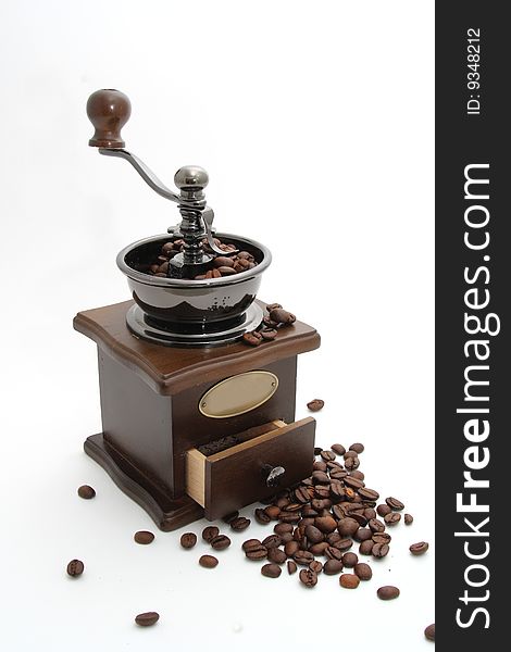 Manual coffee grinder and coffee grains on a white background