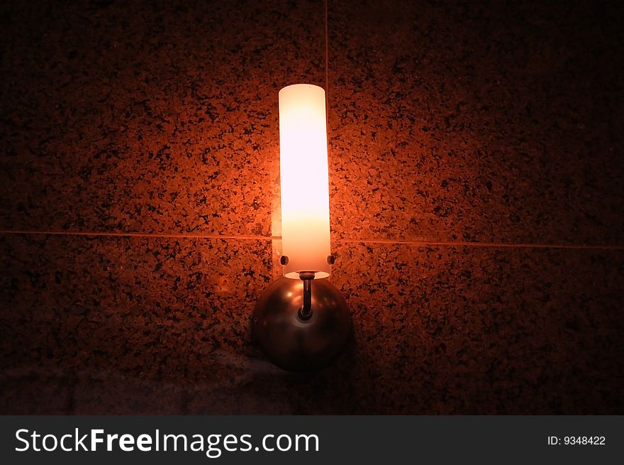 Glowing orange lamp on a tile wall